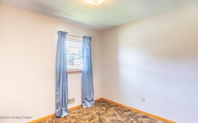 empty room with carpet floors, visible vents, and baseboards