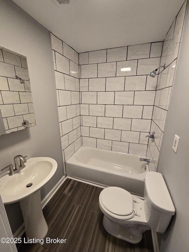 full bath featuring  shower combination, wood finished floors, toilet, and baseboards