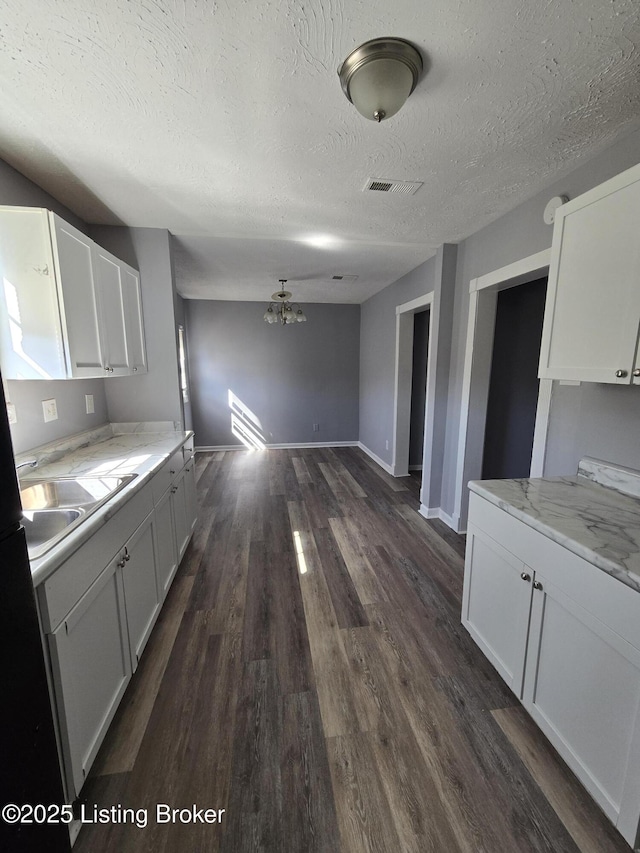 kitchen with dark wood-style flooring, visible vents, a sink, and white cabinetry