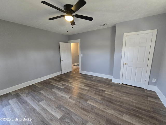 unfurnished bedroom with visible vents, dark wood-type flooring, ceiling fan, a textured ceiling, and baseboards