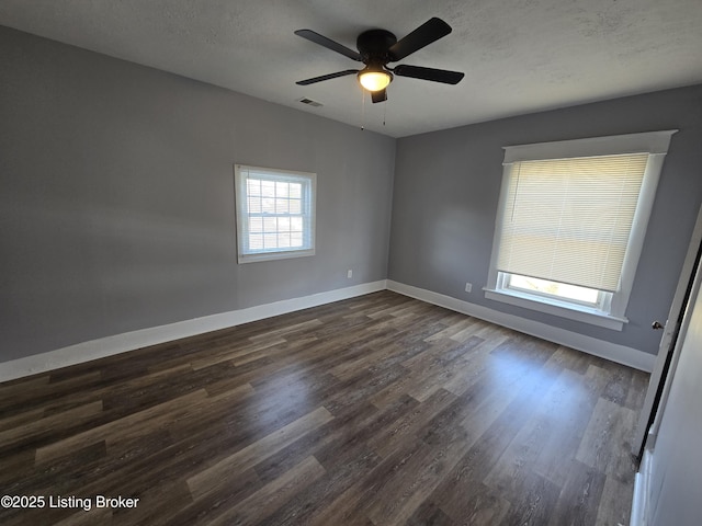 spare room featuring dark wood-style floors, a textured ceiling, visible vents, and baseboards