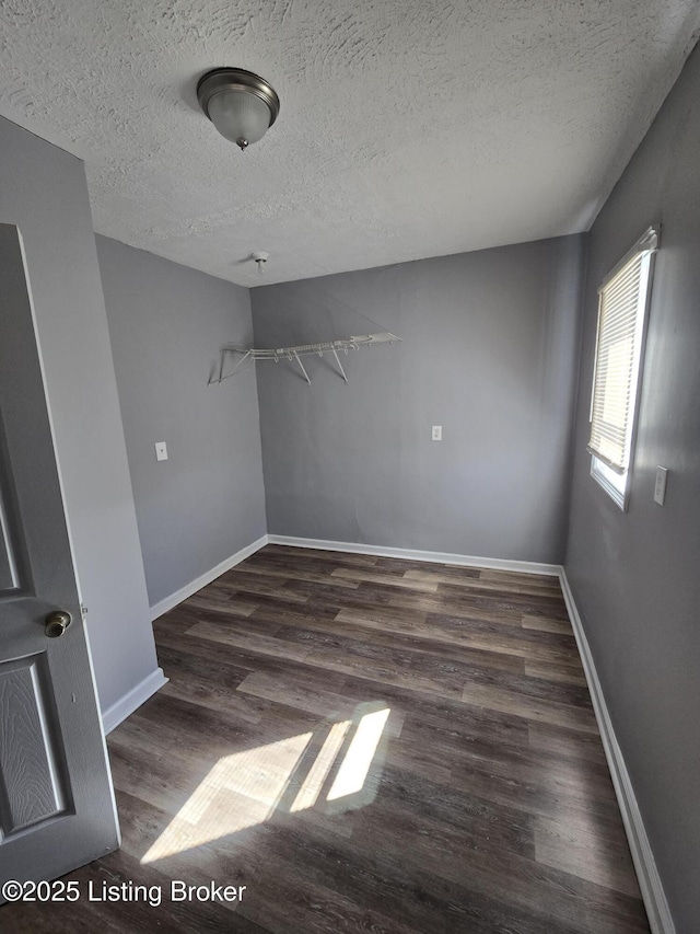 unfurnished room featuring a textured ceiling, baseboards, and wood finished floors