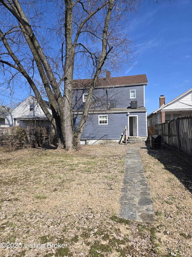 back of property featuring entry steps, fence, and a chimney