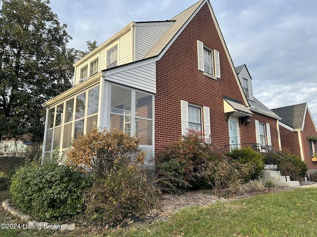 view of side of home with a sunroom and brick siding