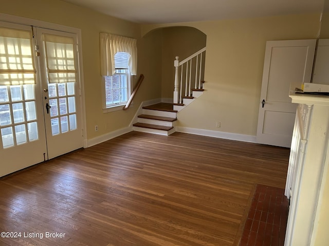 interior space featuring stairs, arched walkways, dark wood finished floors, and baseboards