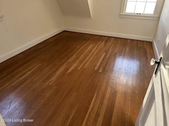 empty room with baseboards and dark wood-type flooring