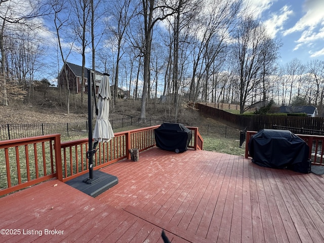 wooden terrace with a fenced backyard and a grill