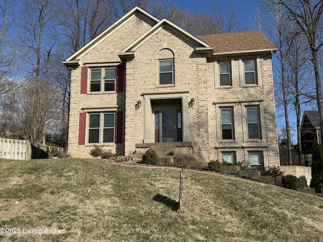 view of front facade featuring brick siding, a front lawn, and fence