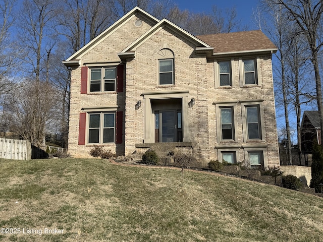 view of front of home with a front yard, fence, and brick siding