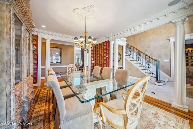 dining space featuring a chandelier, wood finished floors, decorative columns, and crown molding