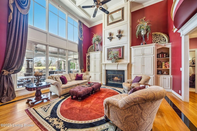 living area featuring crown molding, a towering ceiling, and wood finished floors