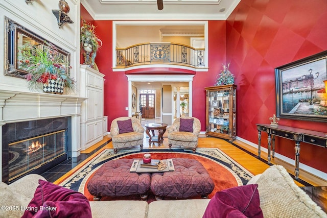 living area with baseboards, a fireplace, ornamental molding, and wood finished floors