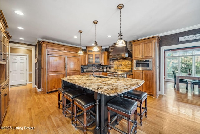 kitchen featuring custom exhaust hood, stainless steel oven, brown cabinets, and a sink