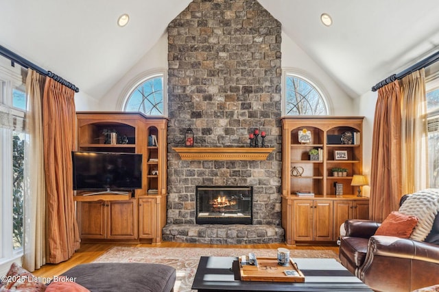 living area with a wealth of natural light, a large fireplace, light wood-style flooring, and recessed lighting