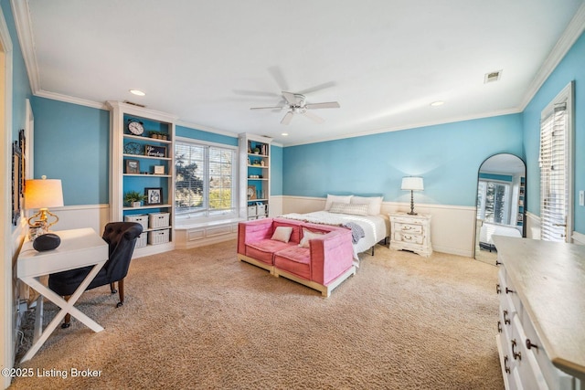 carpeted bedroom with ornamental molding, wainscoting, and multiple windows