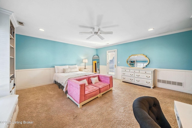 carpeted bedroom with ornamental molding, wainscoting, and visible vents