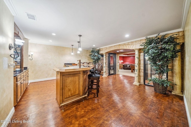 kitchen with ornate columns, arched walkways, dark wood-style flooring, and ornamental molding