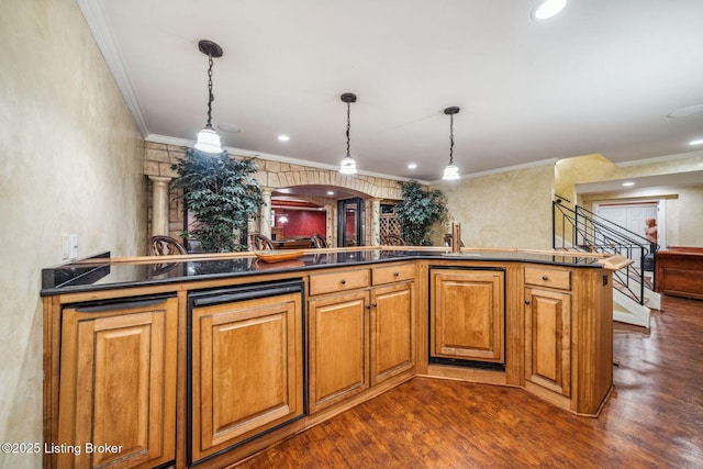 kitchen featuring hanging light fixtures, ornamental molding, dark wood-style floors, brown cabinetry, and dark countertops