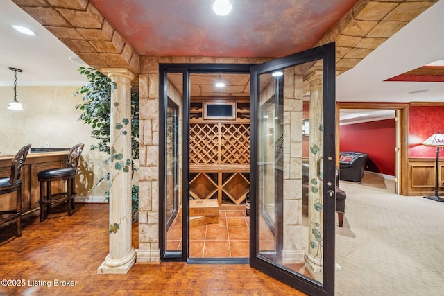 wine room with a bar, decorative columns, and crown molding