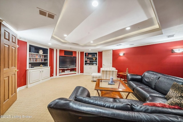 living room featuring carpet, built in shelves, visible vents, and a raised ceiling