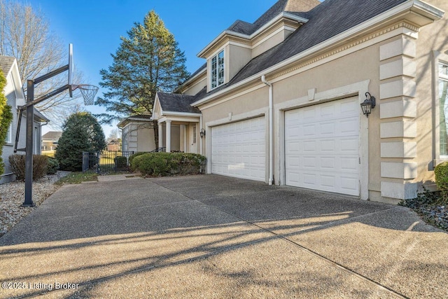 view of side of property with concrete driveway, roof with shingles, fence, and stucco siding