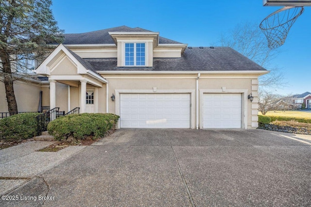 view of front of property with concrete driveway, roof with shingles, an attached garage, and stucco siding