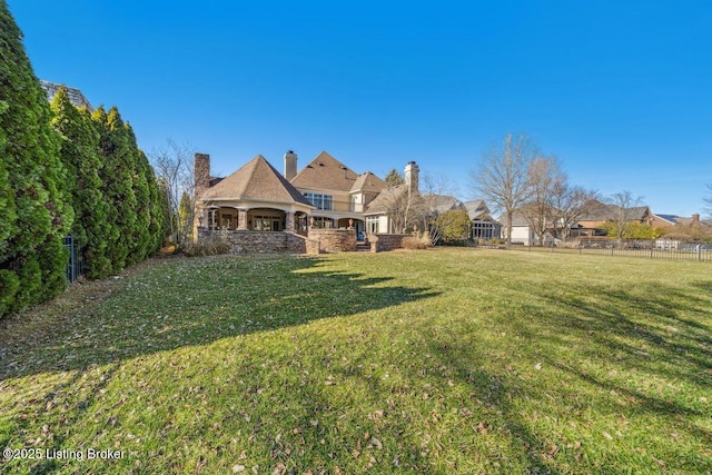 back of property featuring a yard and fence