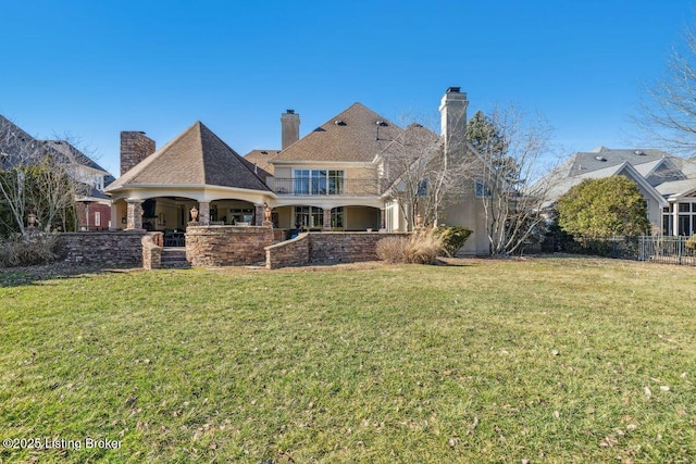 back of house with a lawn, a chimney, and fence