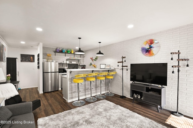 living area featuring recessed lighting, brick wall, and wood finished floors