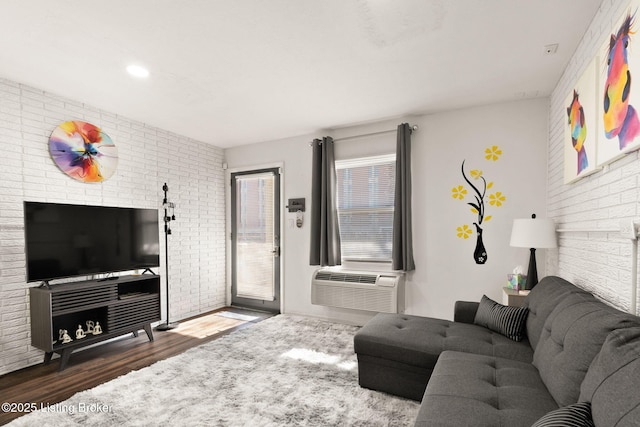 living room featuring brick wall, cooling unit, and wood finished floors