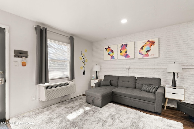 living area featuring wood finished floors, brick wall, and a wall mounted AC