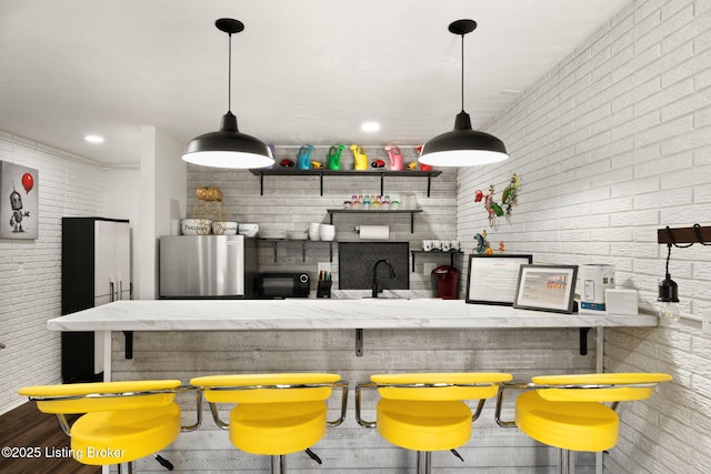 bar featuring recessed lighting, brick wall, decorative light fixtures, and freestanding refrigerator