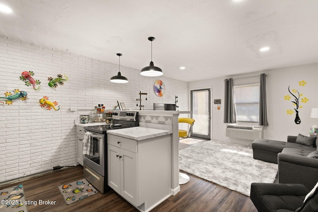 kitchen with electric range, dark wood-type flooring, open floor plan, brick wall, and a peninsula