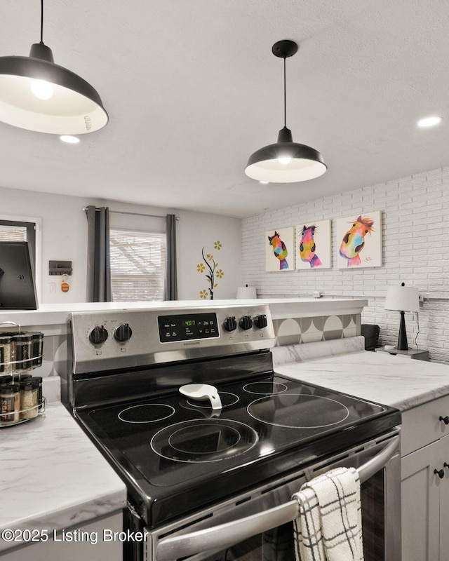 kitchen with light stone counters, recessed lighting, electric range, hanging light fixtures, and tasteful backsplash