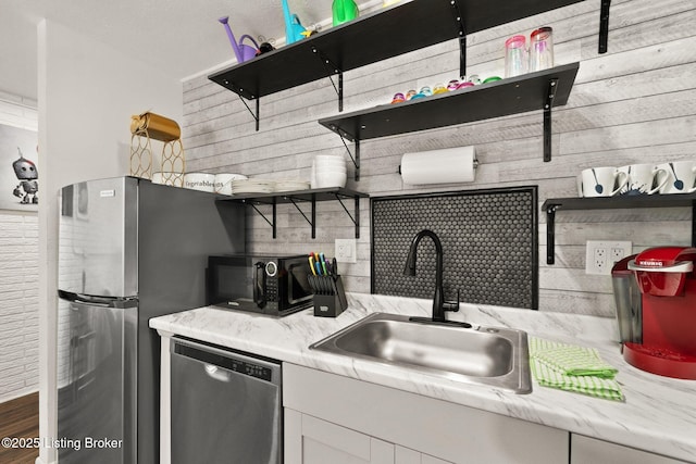 kitchen featuring decorative backsplash, appliances with stainless steel finishes, light countertops, open shelves, and a sink