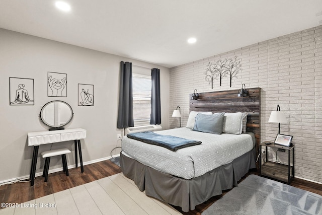 bedroom featuring brick wall, baseboards, wood finished floors, and recessed lighting