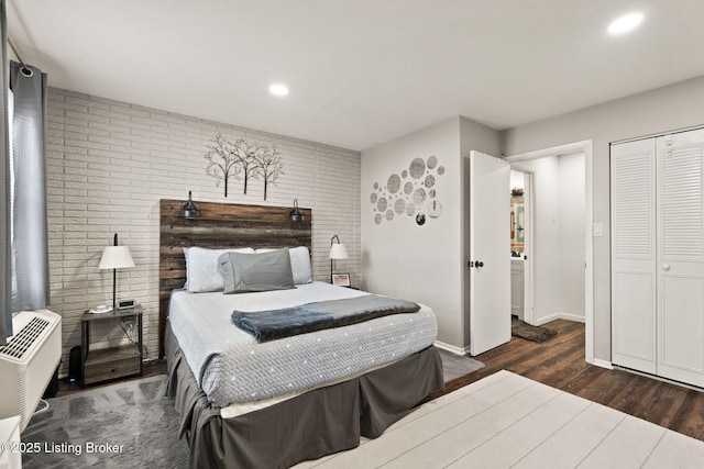 bedroom featuring brick wall, baseboards, wood finished floors, and recessed lighting