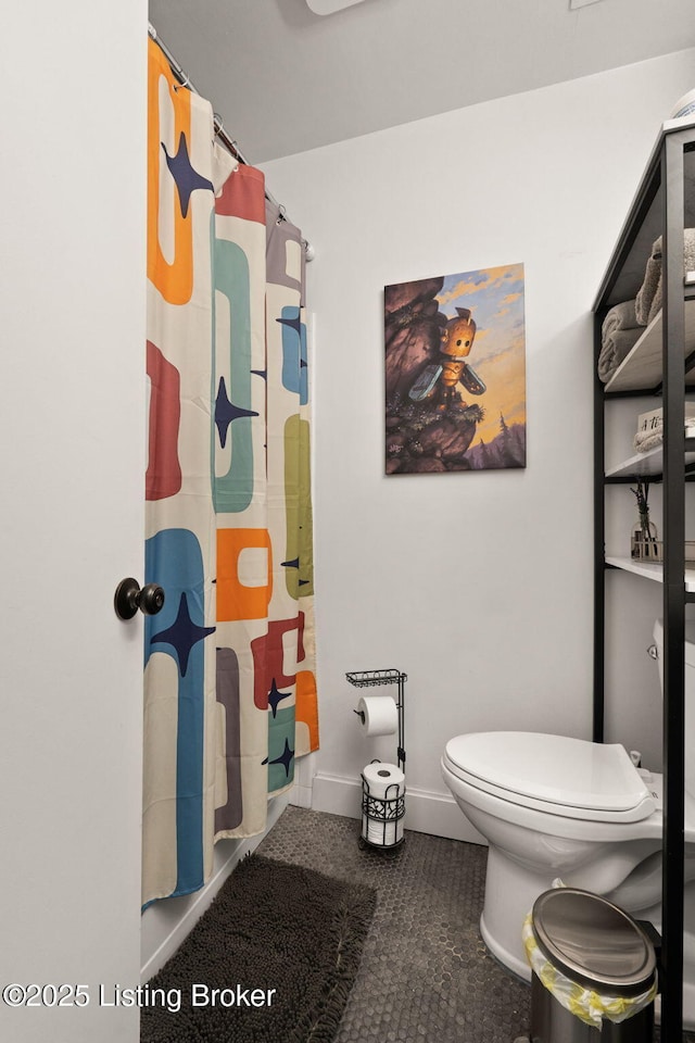 full bathroom featuring toilet, baseboards, and a shower with shower curtain