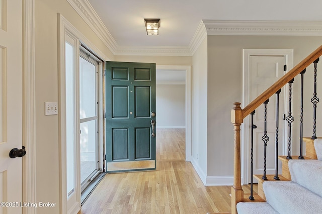 entryway with stairs, ornamental molding, light wood-style flooring, and baseboards