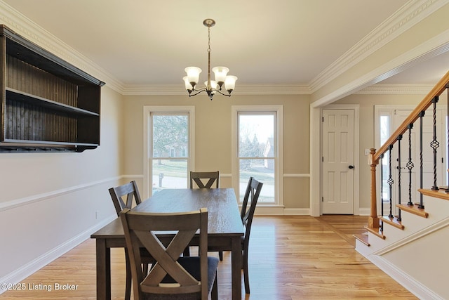 dining space with light wood-style floors, ornamental molding, an inviting chandelier, and stairs