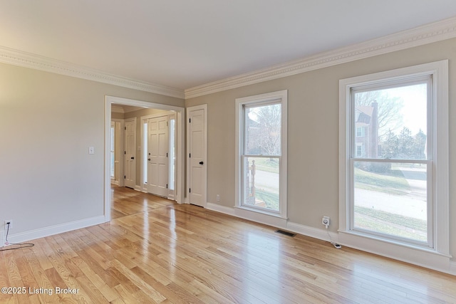 unfurnished room with light wood finished floors, baseboards, visible vents, and ornamental molding