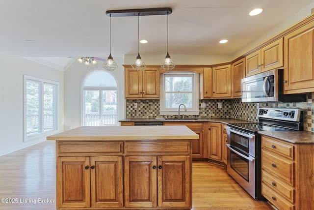 kitchen with tasteful backsplash, a kitchen island, appliances with stainless steel finishes, light wood-style floors, and a sink