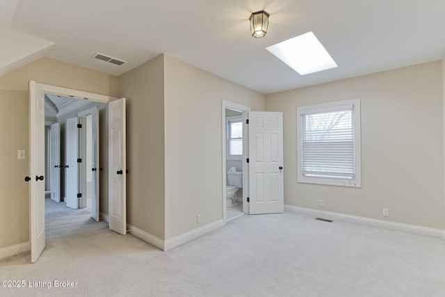 unfurnished bedroom with carpet floors, a skylight, baseboards, and visible vents