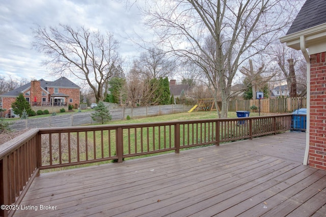 wooden deck featuring a yard, a playground, and fence