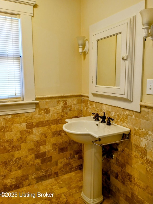 bathroom featuring a wainscoted wall and tile walls