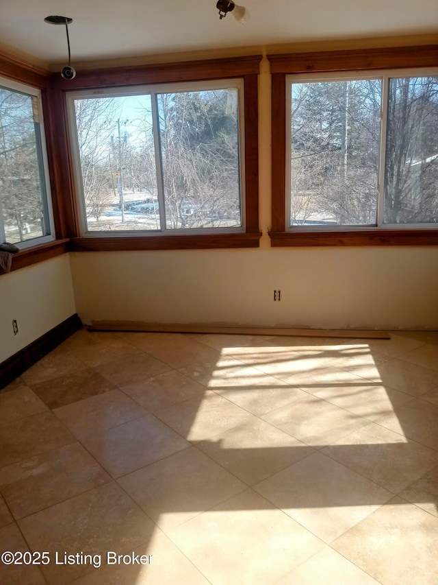 tiled spare room with baseboards and a wealth of natural light