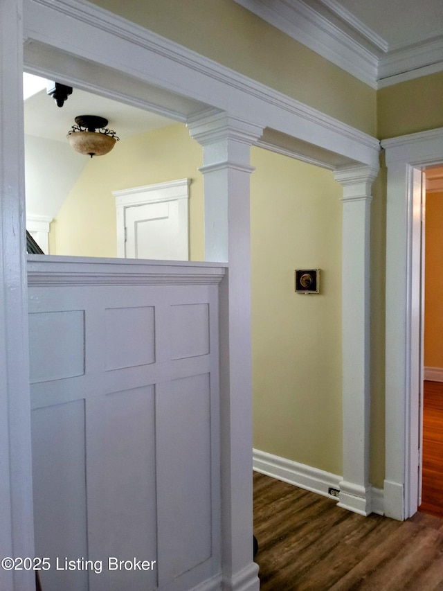 interior space with crown molding, dark wood-style flooring, decorative columns, and baseboards