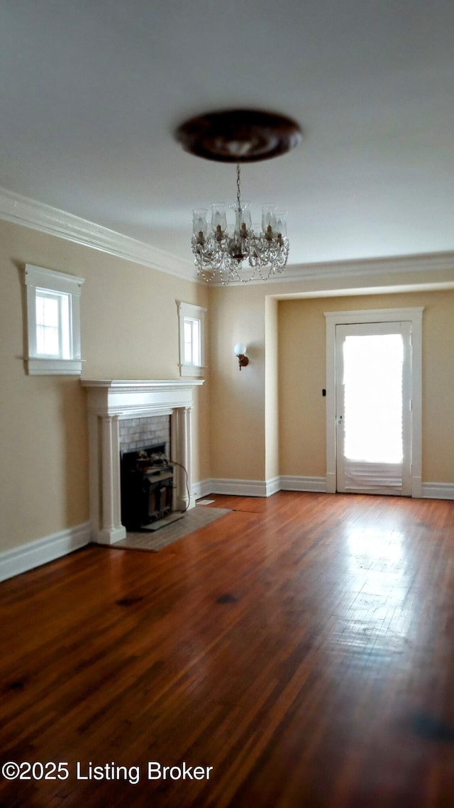 unfurnished living room with baseboards, a chandelier, wood finished floors, and crown molding