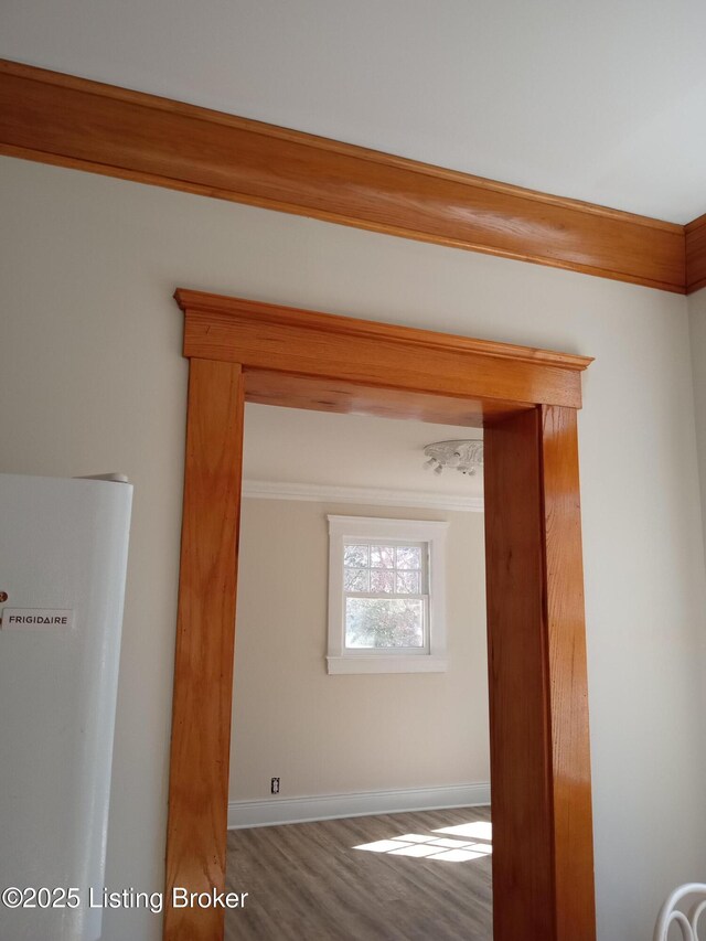 unfurnished room featuring ornamental molding, baseboards, and wood finished floors