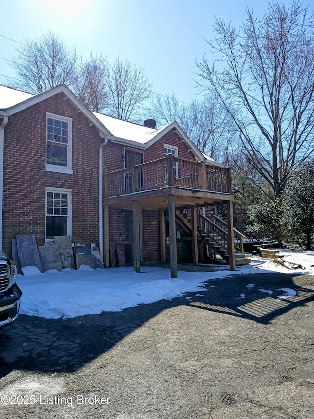 exterior space with a wooden deck, stairs, and brick siding